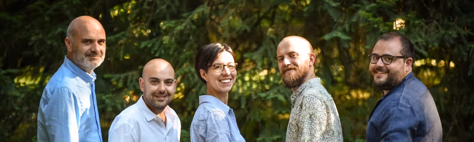 5 smiling people in a sunny green outdoor space